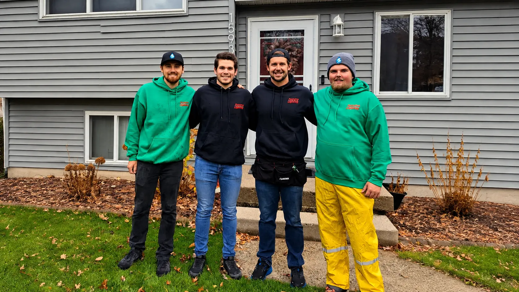 PurePro Cleaning holiday lighting team in West Michigan - four crew members in hoodies outside a home