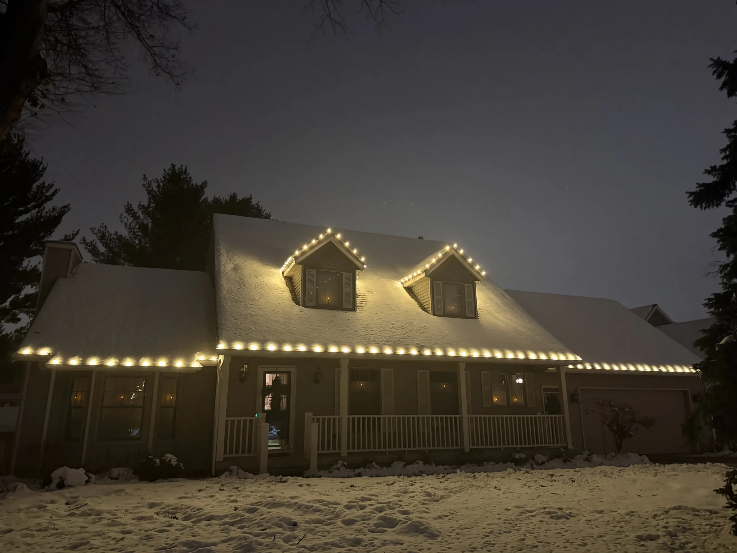 Christmas light installation in West Michigan - Cape Cod home with white lights on roofline and dormers