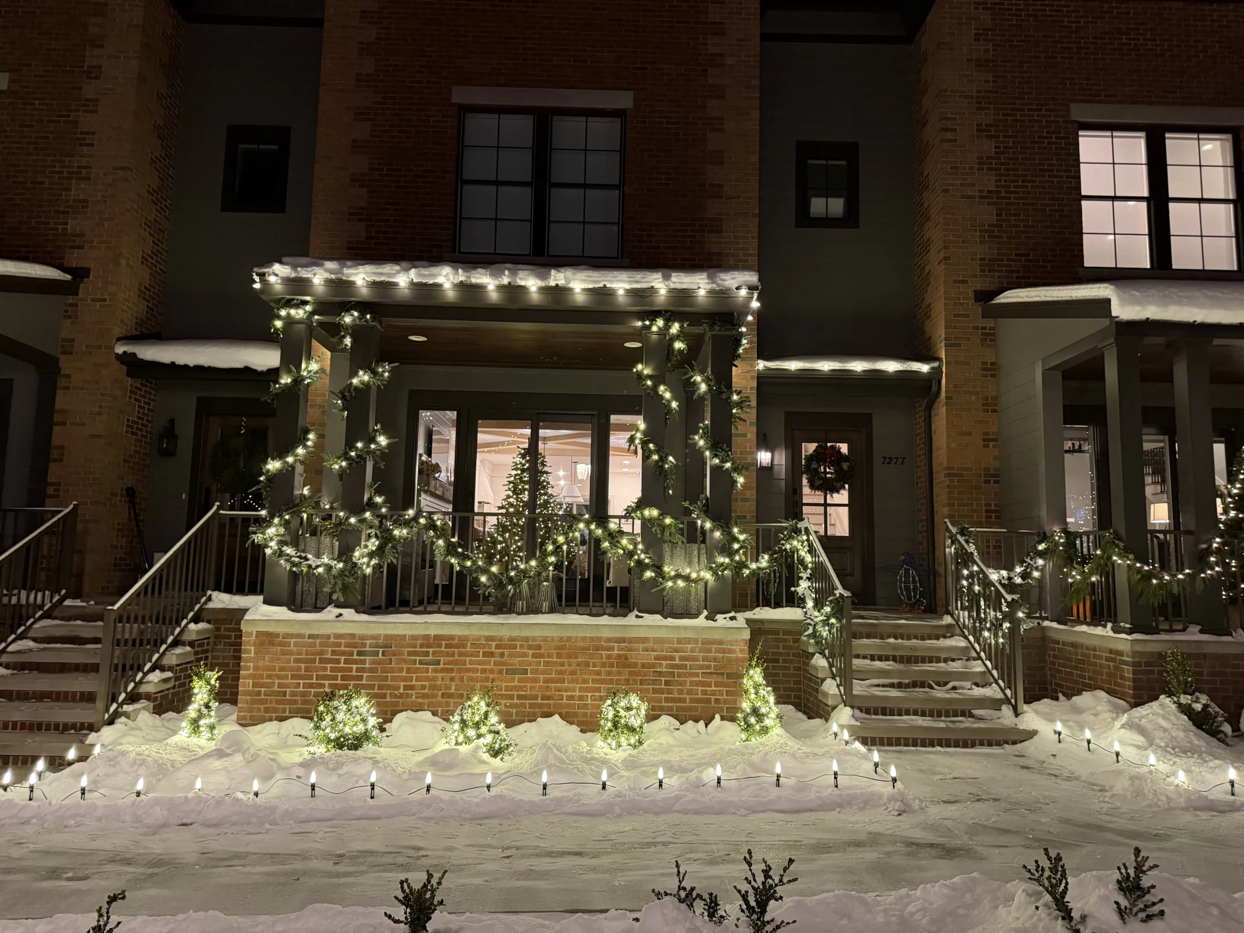 Christmas light installation in East Grand Rapids, Michigan - brick townhome porch with lit garland and path lights