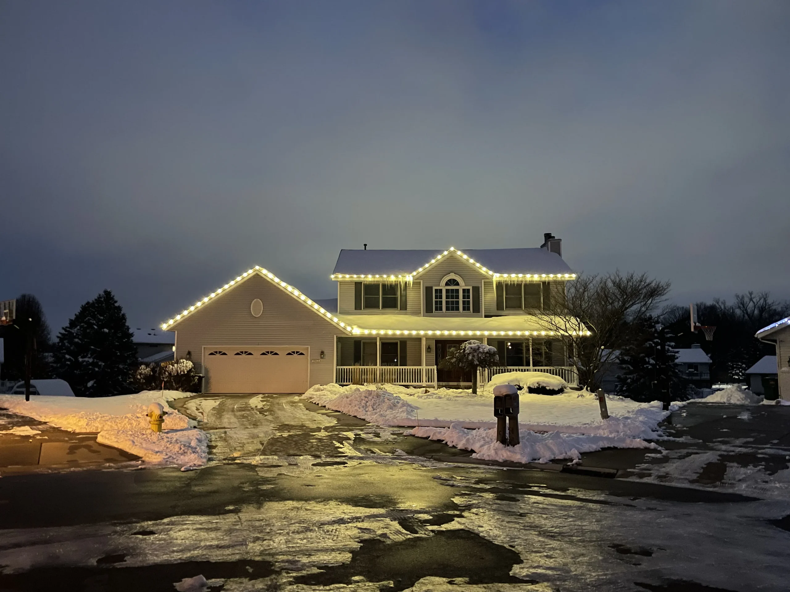 Christmas light installation in Grandville, Michigan - two-story home with warm white roofline lights at dusk
