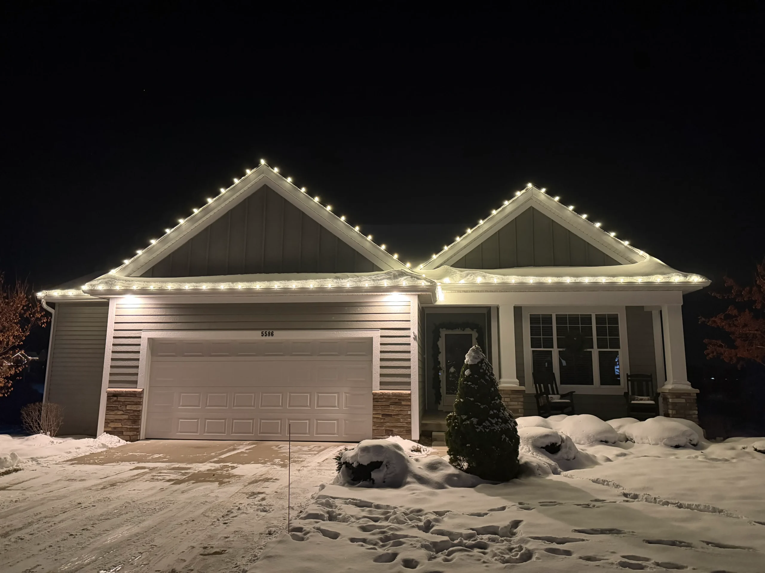 Christmas light installation in Hudsonville, Michigan - ranch home with white roofline lights on a snowy night